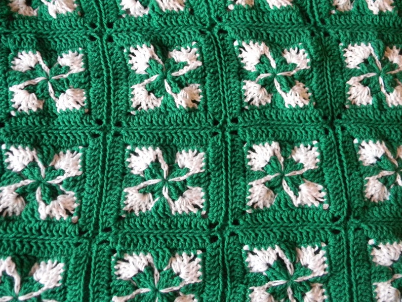 May include: Green and white crocheted blanket with a repeating pattern of four-leaf clover motifs.