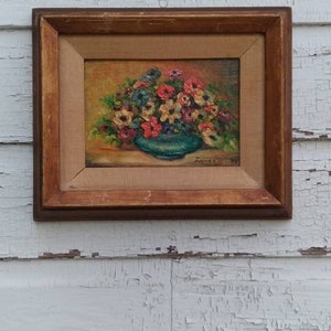 May include: A framed painting of a bouquet of flowers in a blue vase. The flowers are pink, white, and yellow. The painting is on a white background.