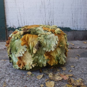 May include: A green, brown, and orange velvet hat shaped like a cluster of leaves.