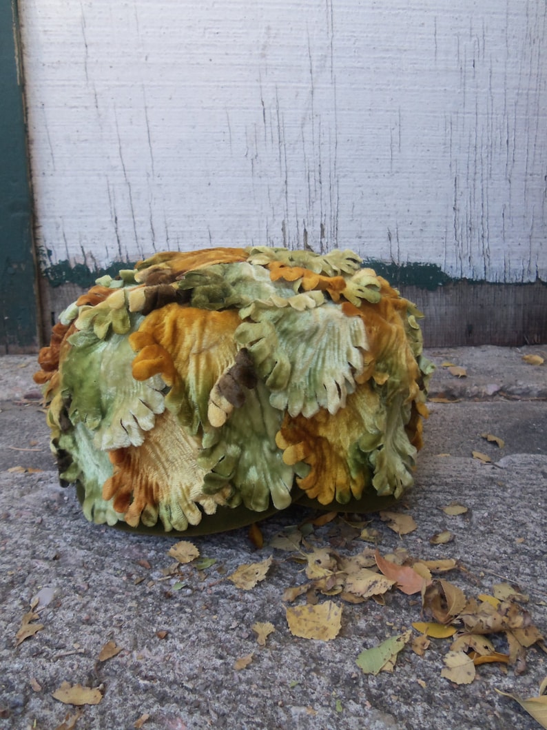 May include: A green, brown, and orange velvet hat shaped like a cluster of leaves.