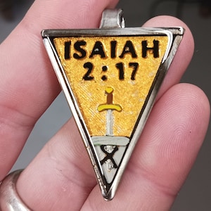 May include: A triangular silver pendant with a gold background. The pendant features the text "ISAIAH 2:17" in black lettering and a silver sword with a brown handle.
