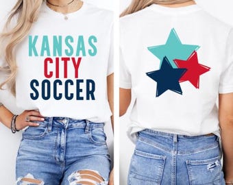 May include: White t-shirt with "KANSAS CITY SOCCER" printed on the front and three stars in red, blue, and turquoise on the back.