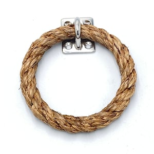 May include: A natural rope ring with a silver metal hook attached to a wall. The rope is brown and has a natural texture.
