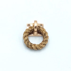 May include: A gold-toned rope handle with a square base. The rope is wrapped around a metal ring.