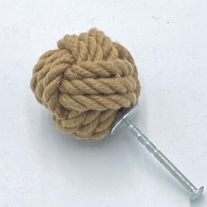 Può includere: Un pomello a nodo di corda marrone con una vite argentata. Il pomello è fatto di corda naturale e ha un aspetto rustico.