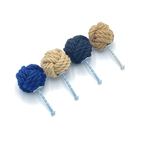 以下が含まれることがあります： 紺色、黒、ベージュ、茶色の金属ネジが付いたロープの結び目が4つあります。