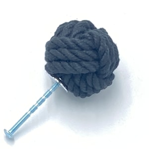 Op de afbeelding: Zwarte touwkastknop met een zilveren schroef. Het touw is in een knoop geknoopt om een ronde knop te vormen.