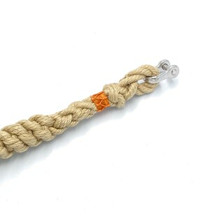 May include: A beige braided rope with an orange accent and a silver metal swivel snap hook.