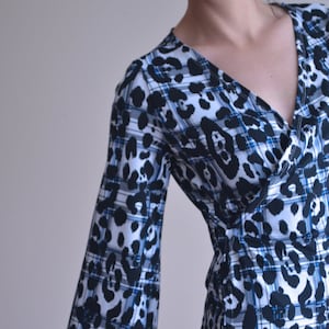 Puede incluir: Una blusa de manga larga con estampado de leopardo en blanco y negro y estampado de cuadros azules.