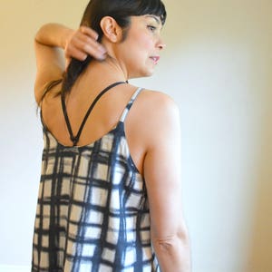 May include: A black and white checked tank top with thin black straps. The tank top is made of a soft, flowing fabric.