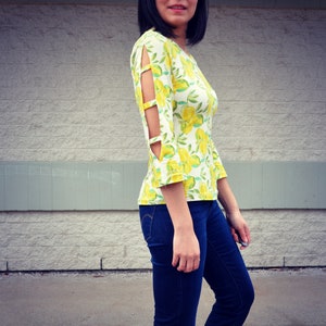 May include: A white and yellow floral print top with cut-out sleeves. The top has a scoop neck and is made of a soft, stretchy fabric.