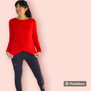May include: A red long-sleeved top with a twist detail at the front, worn with black leggings.