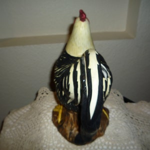 Peut inclure: Figurines de coq en c&eacute;ramique noire et blanche avec une cr&ecirc;te et des barbillons rouges. Le coq est debout sur une base brune.