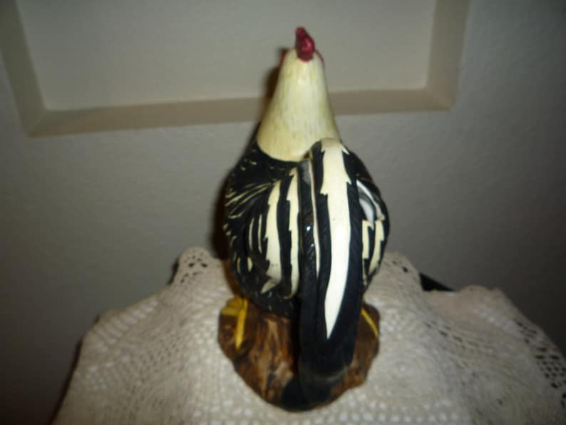 Peut inclure: Figurines de coq en c&eacute;ramique noire et blanche avec une cr&ecirc;te et des barbillons rouges. Le coq est debout sur une base brune.