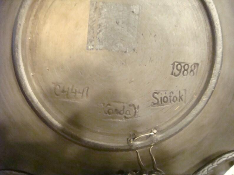 May include: Close-up of the bottom of a ceramic plate with the numbers 1988 and 2441, the word "Siofok" and the word "Garda" written on it.