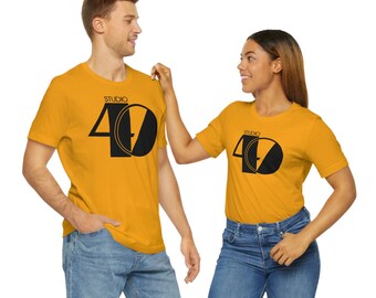 May include: Two people wearing matching yellow t-shirts with a black graphic of the number 40 and the word "Studio" above it.