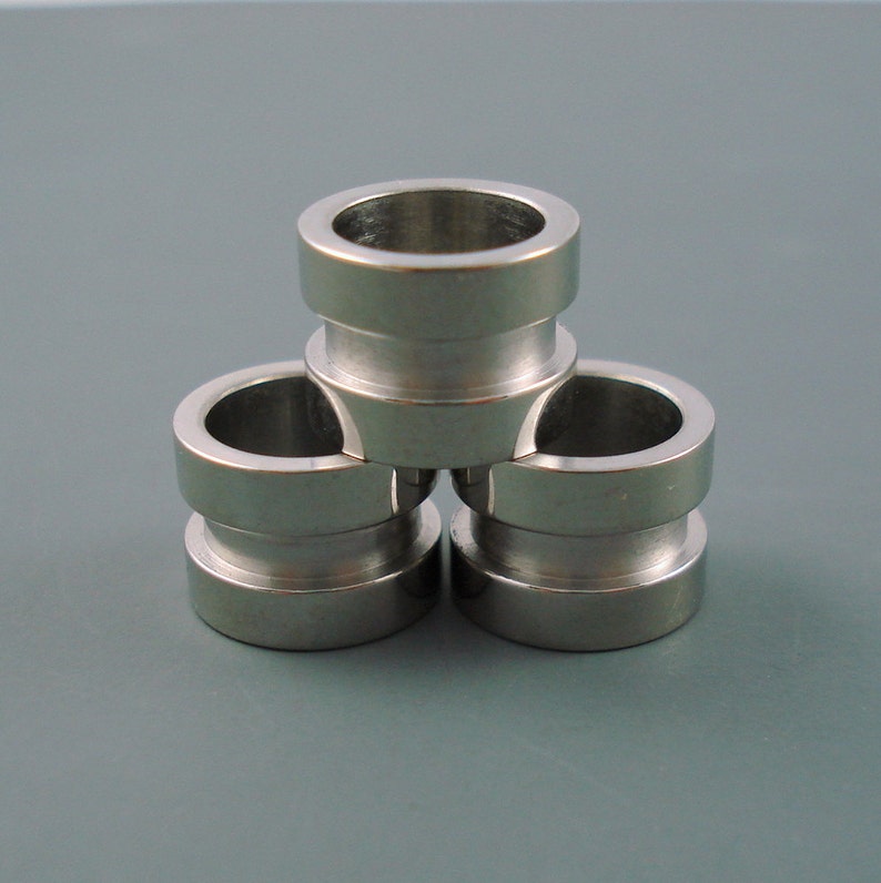 May include: Three silver metal rings stacked on top of each other. The rings are smooth and have a shiny finish.