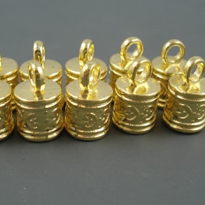 May include: Ten gold-colored metal cord ends with a decorative design and a loop at the top.