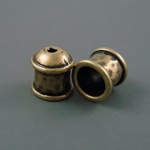 May include: Two antique gold-toned metal beads with a textured finish. The beads are round and have a hole in the center.