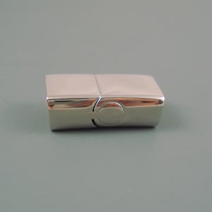 May include: A silver magnetic clasp for a bracelet or necklace. The clasp is made of two rectangular pieces that snap together.