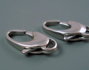 May include: Two silver metal lobster clasps, a common type of fastener used in jewelry making.