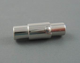 May include: A silver magnetic clasp for a bracelet or necklace. The clasp is cylindrical and has a small ball on one end.