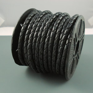 May include: A spool of black braided leather cord. The cord is wound tightly around a black plastic spool.
