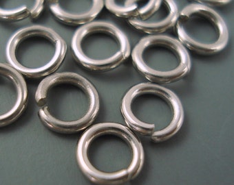 May include: A close-up of a pile of silver jump rings. The rings are all the same size and are arranged in a random pattern.
