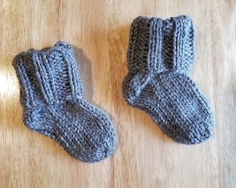 May include: A pair of grey knitted baby booties with folded cuffs.