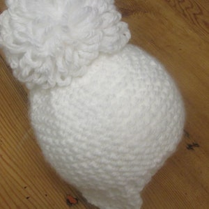 May include: White crocheted beanie with a large white pom-pom on top.