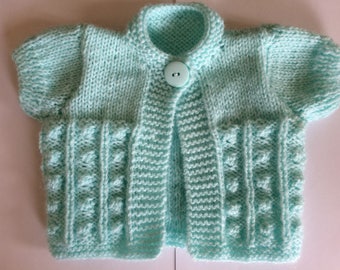 Modello ai ferri n. 50 PDF per realizzare un cardigan bolero a maniche corte da bambina, in 5 taglie dalla nascita ai 12 mesi.