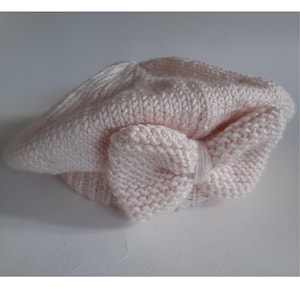May include: A pink knitted beret with a bow on top. The beret is for babies and toddlers and comes in sizes 0-6, 6-12 months, 1-2 years, and 2-3 years.