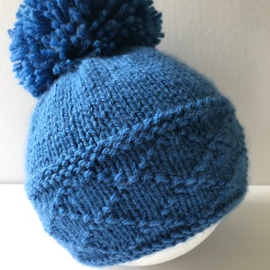 PDF-stickmönsterinstruktioner för att sticka en pom-pom-mössa till baby, pojke eller flickor, i storlekarna: För tidigt född, Nyfödd, 0-3, 3-6, 6-9 och 9-12 månader.