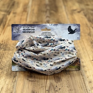 Peut inclure: Tour de cou multifonctionnel avec un fond beige et un motif d'oiseaux, de feuilles et d'accents bleus et gris. L'emballage comprend le texte "Dynamic stretch UPF30 sun protection Moisture-wicking, quick drying."