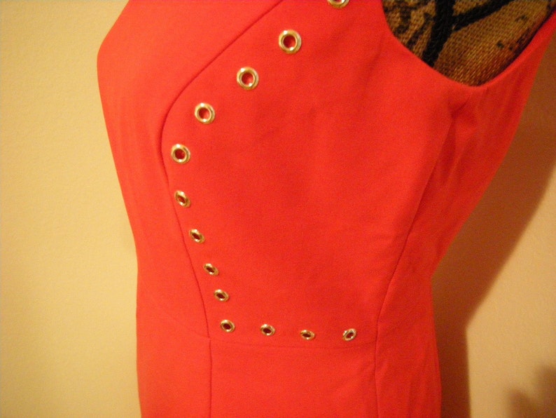 May include: A bright red sleeveless dress with a diagonal row of gold eyelets.