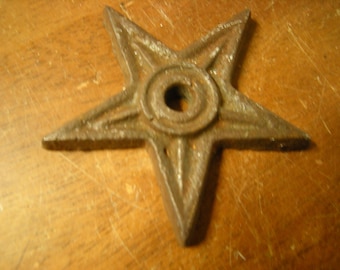May include: A rusty cast iron five-pointed star with a circular hole in the center. The star is a decorative hardware piece.