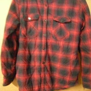 May include: A red and black plaid flannel shirt with a button-up front and long sleeves.