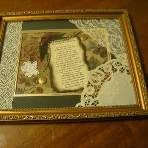 May include: A framed piece of art with a poem about the bond of family. The poem is printed on a cream-colored paper with a floral design. The frame is gold and has a lace border.