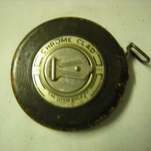 May include: A black and white measuring tape with a chrome clad label and the text "The Lufkin Rule Co."