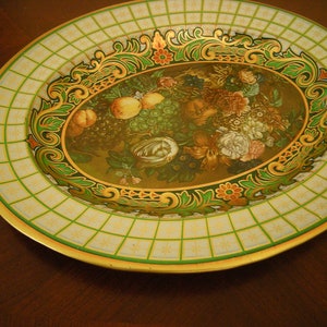 May include: Oval metal serving tray with a green, gold, and white checkered border. The center features a floral design with fruit and grapes.