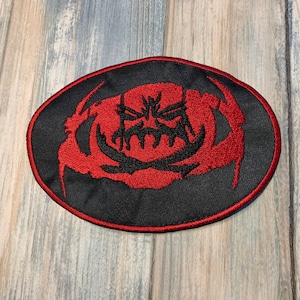 May include: Red embroidered patch with a black background. The patch features a stylized crab with a menacing face.