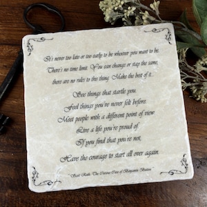 May include: A white stone coaster with an inspirational quote about making the best of life. The quote reads: "It's never too late or too early to be whoever you want to be. There's no time limit. You can change or stay the same, there are no rules to this thing. Make the best of it... See things that startle you. Feel things you've never felt before. Meet people with a different point of view. Live a life you're proud of. If you find that you're not, Have the courage to start all over again."