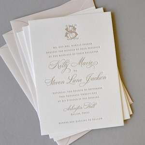 May include: A white wedding invitation with a gold embossed monogram and text. The invitation announces the marriage of Kelly Marie to Steven Lane Jackson on Saturday, September 4th, 2021 at six o'clock in the evening at Arlington Hall in Dallas, Texas. Dinner and dancing to follow.