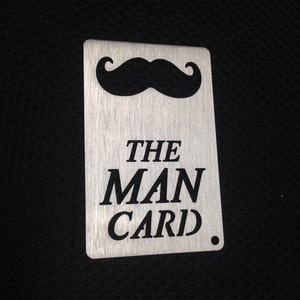 May include: A silver metal card with a black mustache and the text "THE MAN CARD."