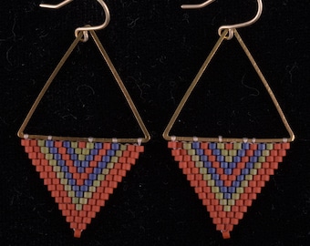 May include: A pair of triangle-shaped earrings with a geometric pattern of red, blue, and green beads. The earrings are made with gold-toned metal.