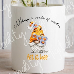 May include: White ceramic mug with a black and white graphic of a gnome wearing a yellow and orange flower crown. The text "Whisper words of wisdom let it bee" is printed on the mug.