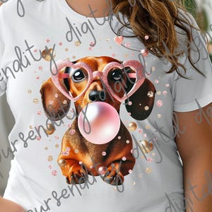 May include: A white t-shirt with a graphic of a dachshund wearing pink heart-shaped sunglasses and blowing a bubble. The background is a white and gold glitter pattern.