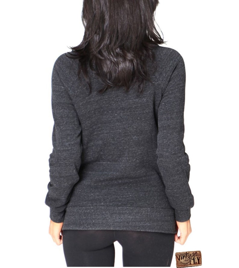May include: Dark gray long-sleeve sweatshirt with a crew neck. The sweatshirt has a heathered texture and fitted sleeves. The model is wearing black leggings. The Vintage Fly logo is visible in the bottom right corner.