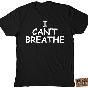 May include: Black t-shirt with the white text "I CAN'T BREATHE". The shirt has a crew neck and short sleeves. A small "Vintage Fly" logo is visible on the bottom right corner.