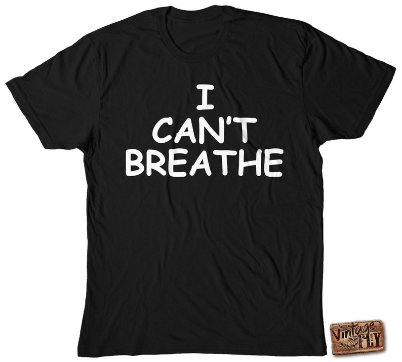 May include: Black t-shirt with the white text "I CAN'T BREATHE". The shirt has a crew neck and short sleeves. A small "Vintage Fly" logo is visible on the bottom right corner.